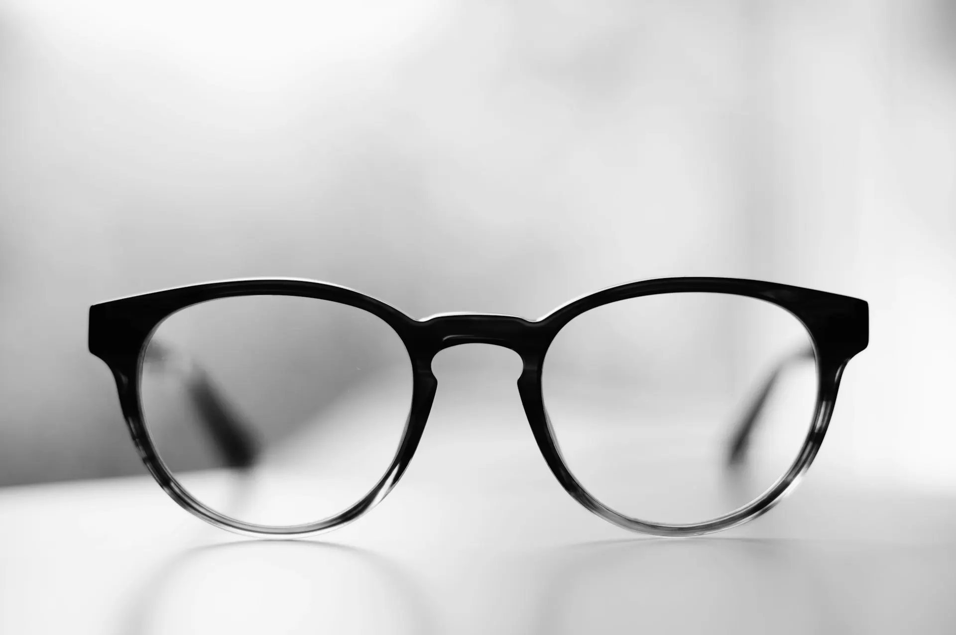 Industry context: Black eyeglass frames in soft light.