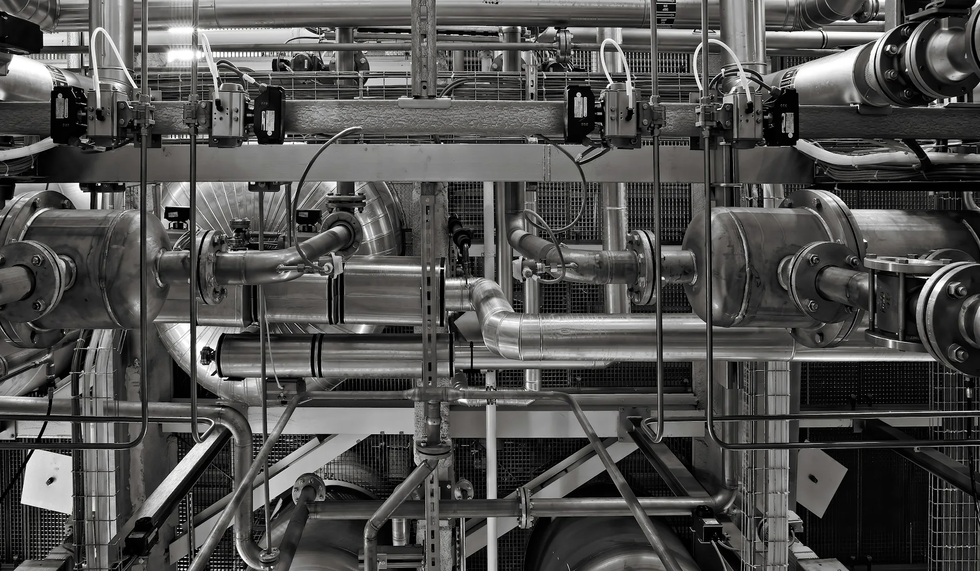 Industry context: Industrial pipework and valves, photographed in black and white.