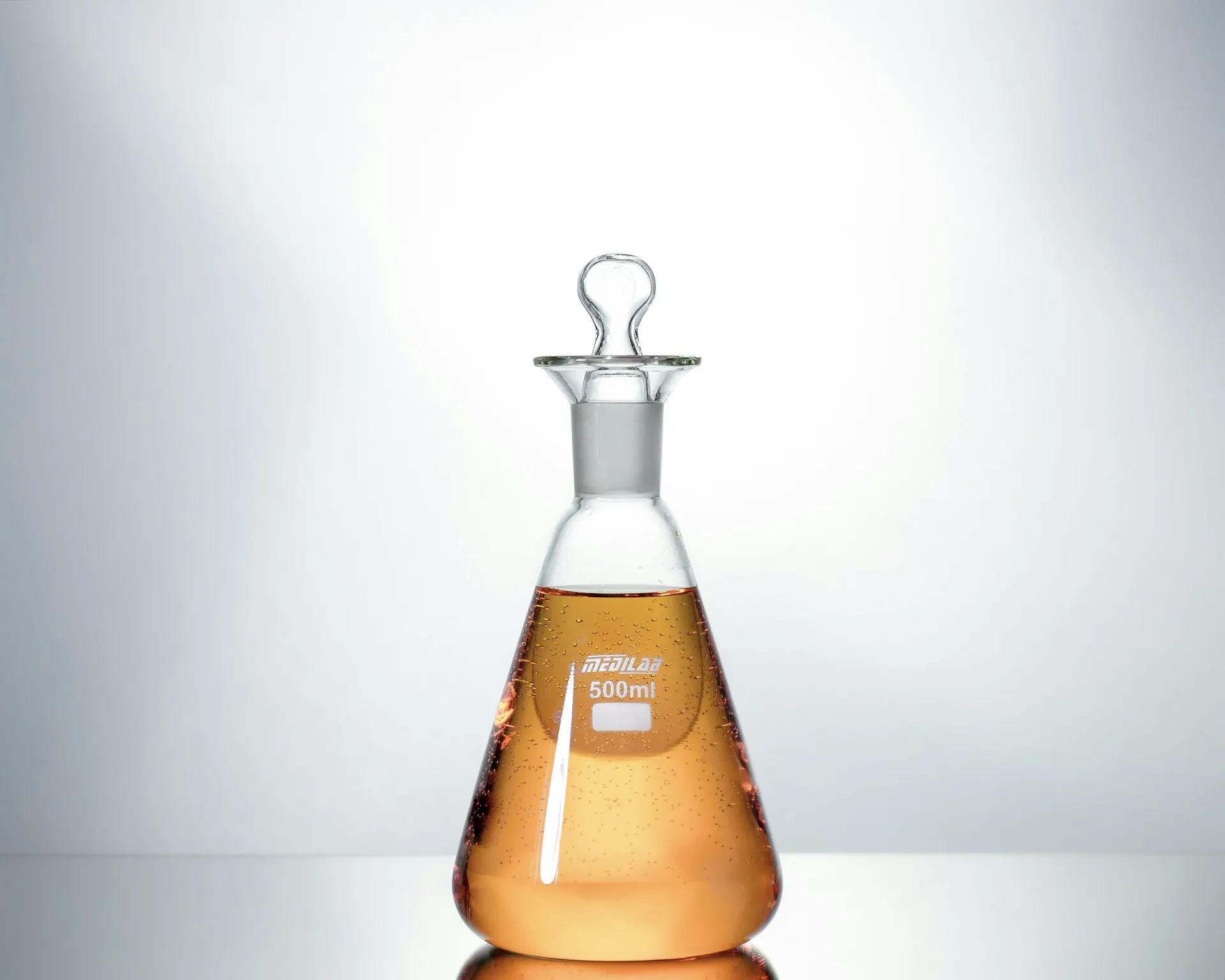 Industry context: Conical laboratory flask containing amber liquid.