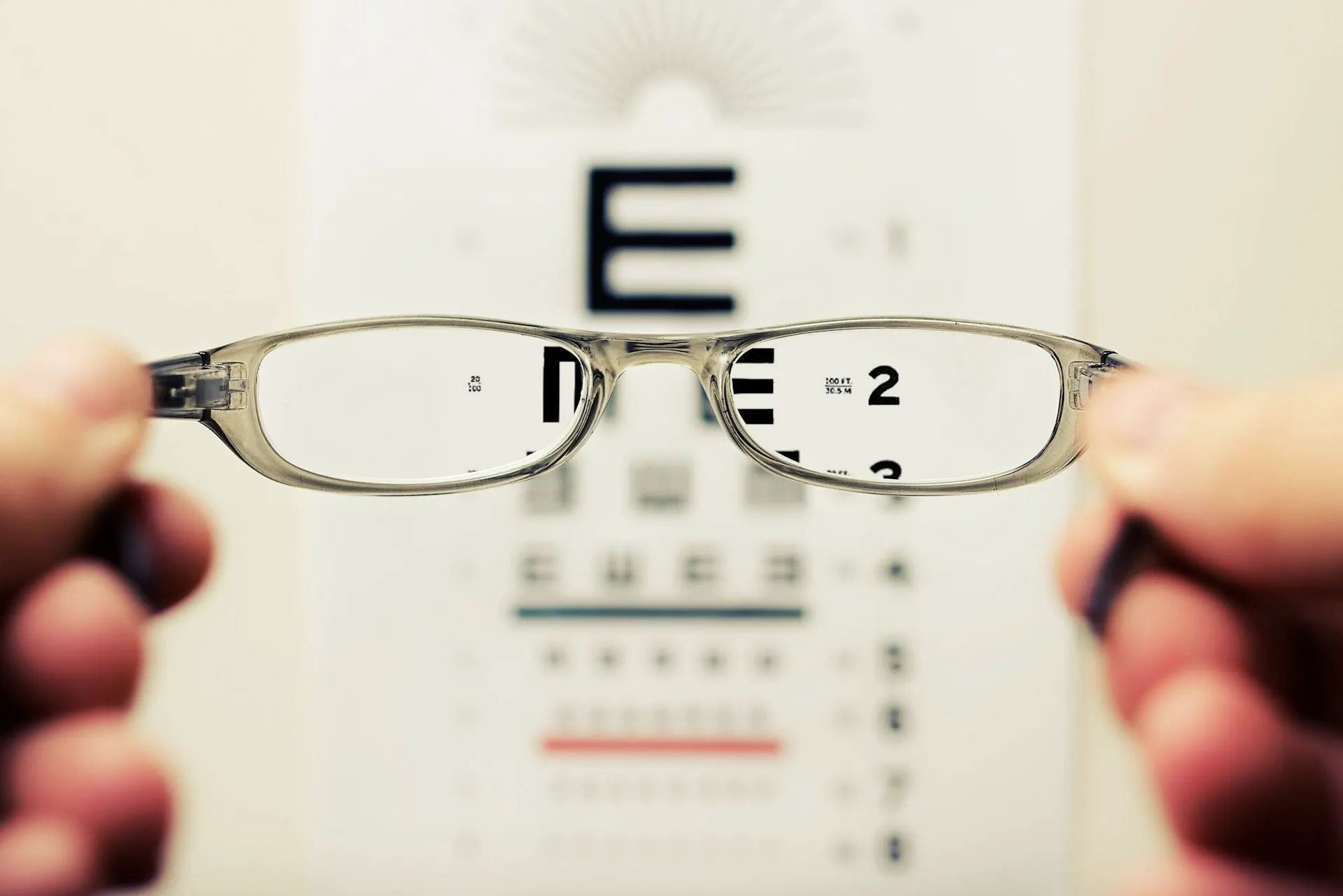 Industry context: Eyeglass lenses held before an eye chart.